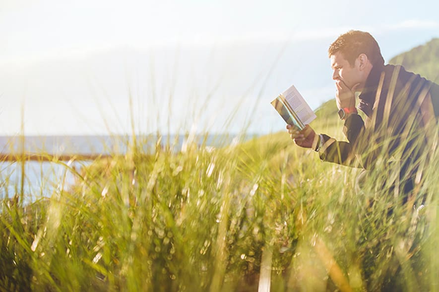 Entspannung mit Hörgeräten steigern - Mann mit Buch auf Bank