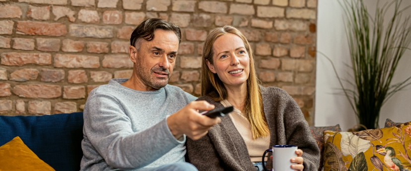 ehepaar mit bluetooth hörgeräten beim fernsehen